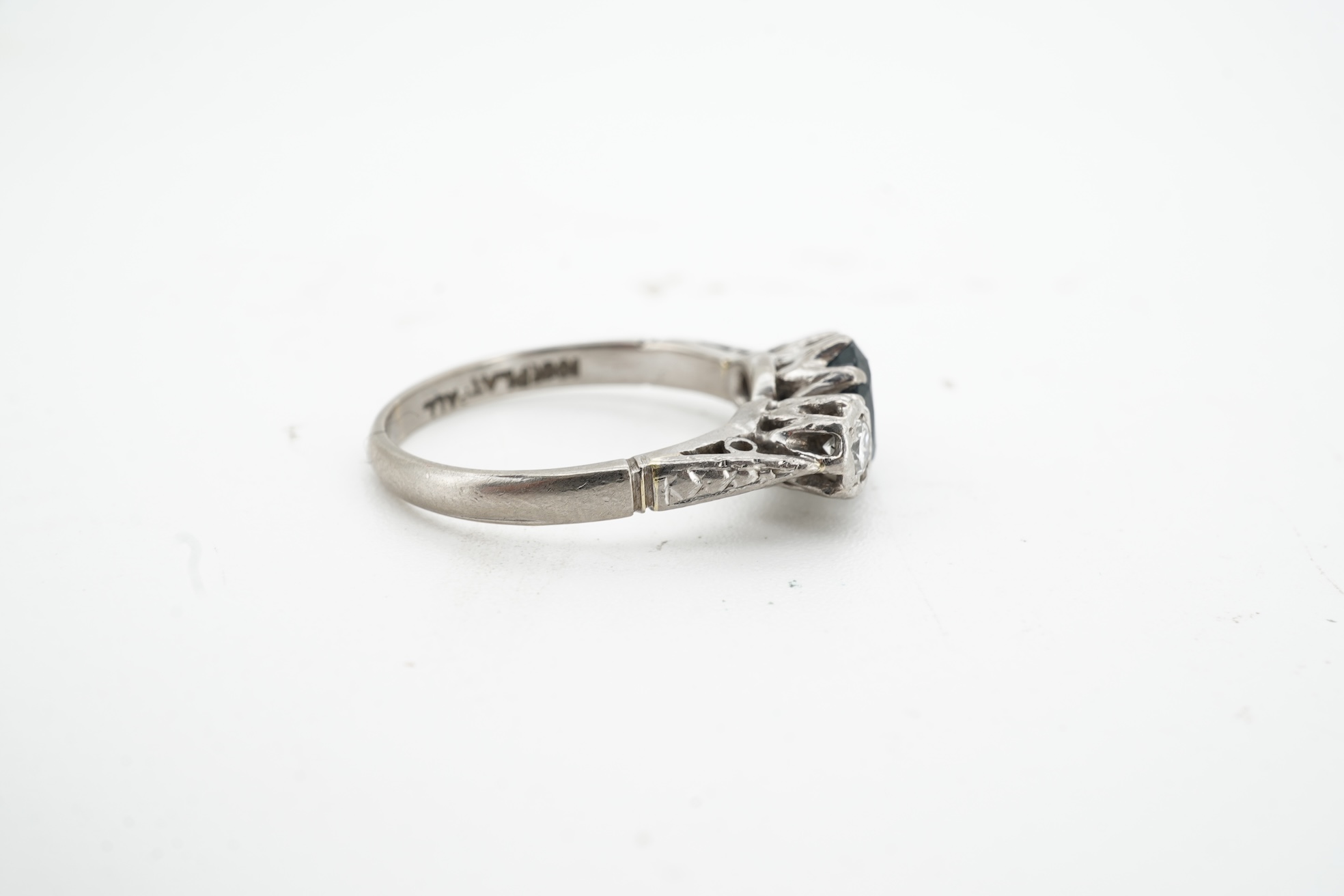 A sapphire and diamond ring, claw-set with an oval sapphire measuring approximately 6.2 x 4.5 x 3.2mm, between shoulders set with brilliant-cut diamonds totalling approximately 0.14 carats, mounted in platinum and pallad